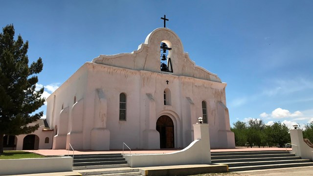 A spanish-colonial style mission underneath a blue sky.