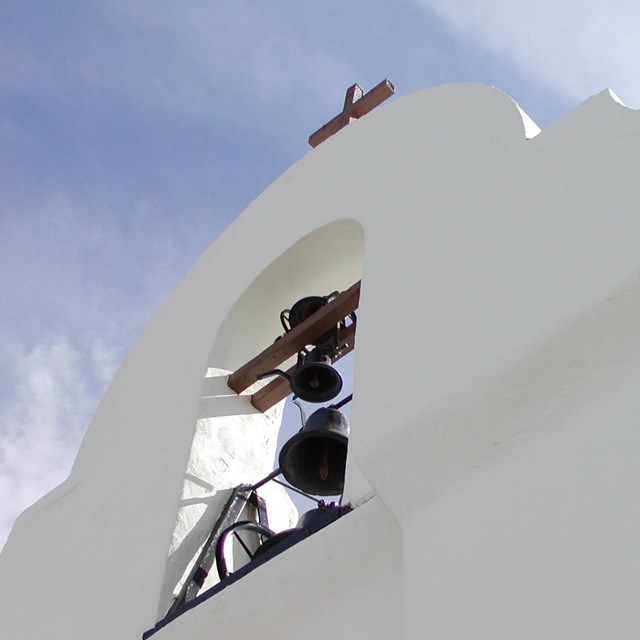 A bell tower of a white stucco church.