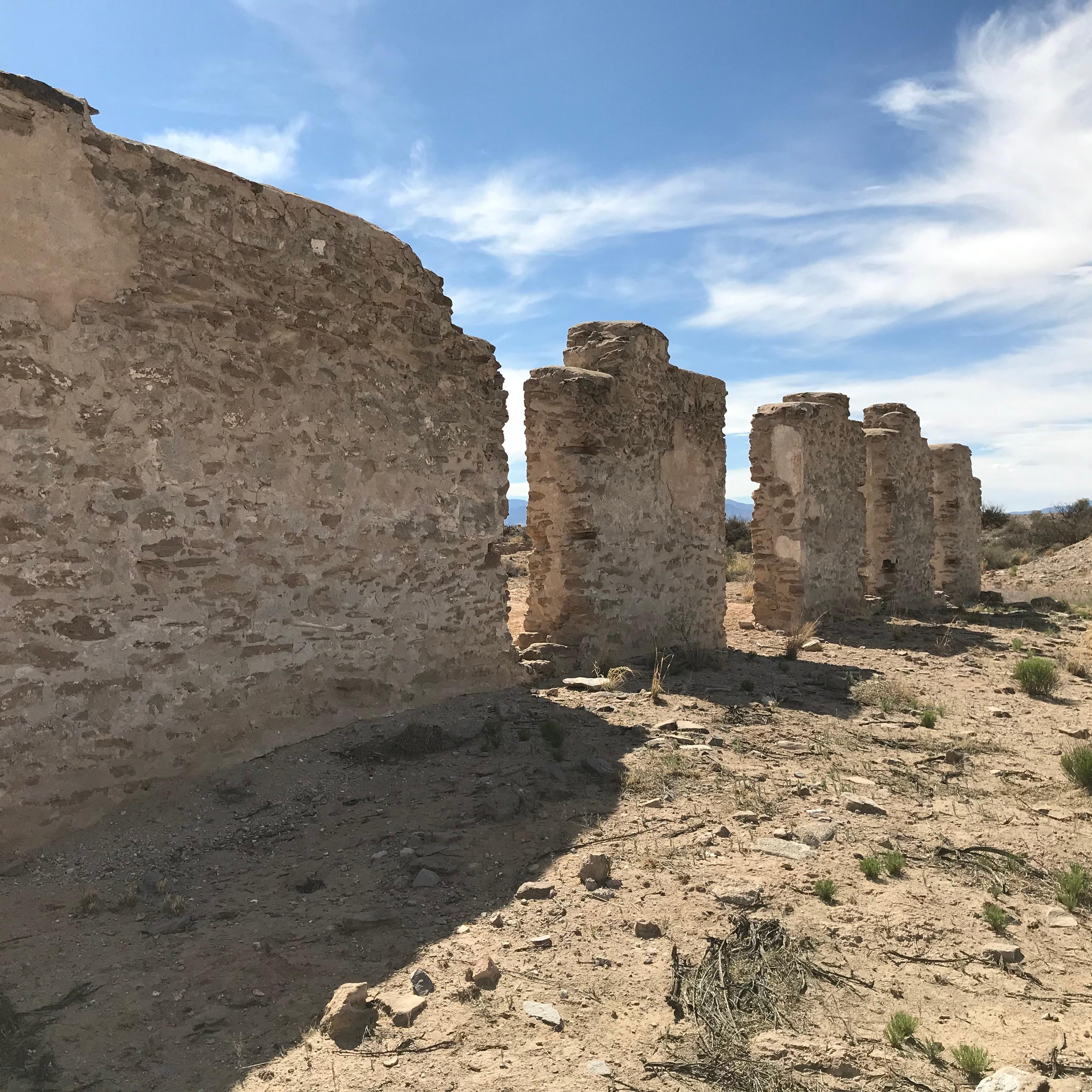 Adobe ruins stand against a stark desert landscape.