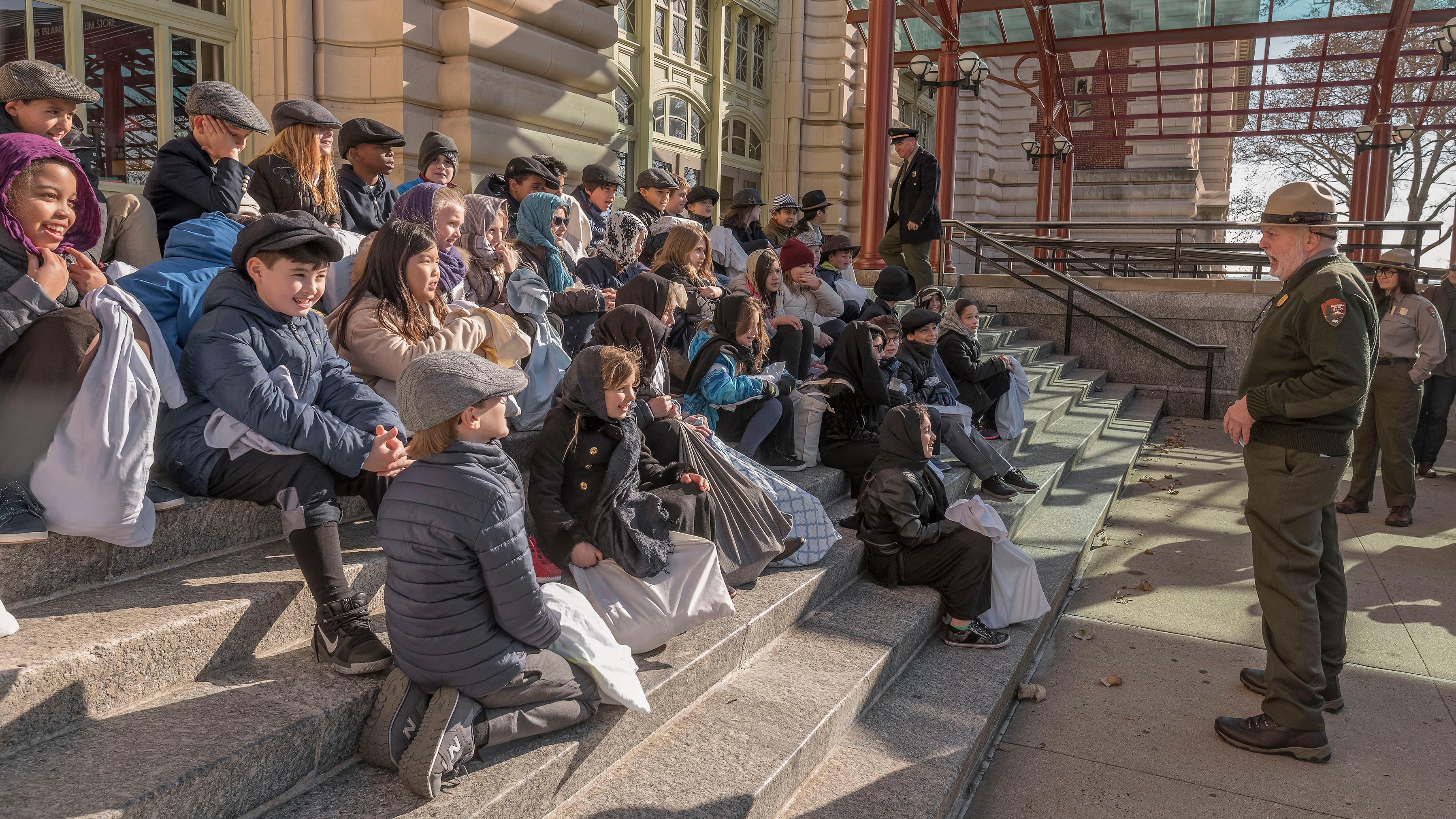 A group of school kids listening to a park ranger talk about Ellis Island
