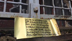 Gold paper brick with message to visitors at old elevator grating on Ellis Island.