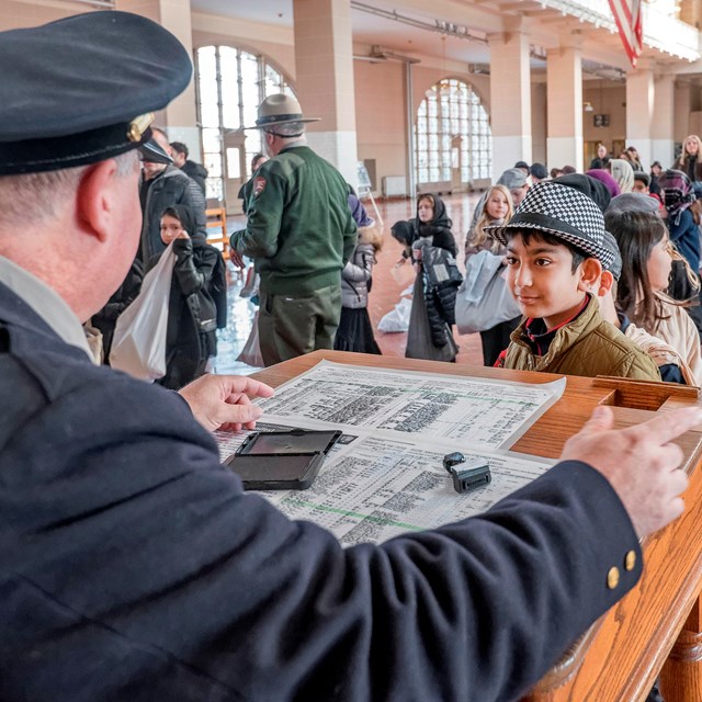 Students lining up to be questioned inside Great Hall on Ellis Island.