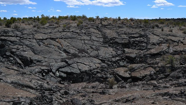 a black lava landscape under blue sky