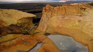 Pools of water on top of a high sandstone bluff.