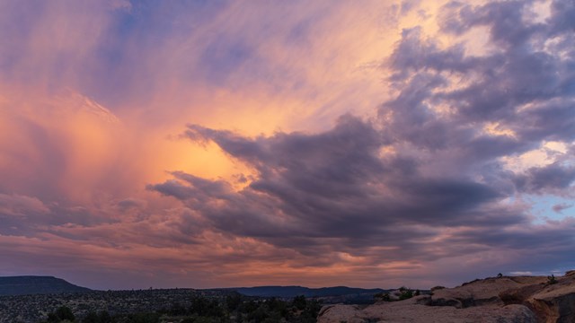 Pink sunset with darker clouds over a sandstone bluff