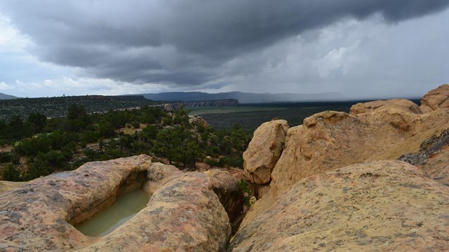 Rain clouds form over sandstone rock.