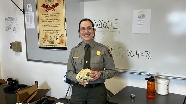Female ranger in a classroom holding a skull