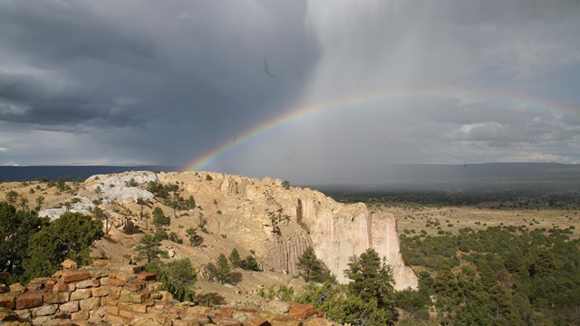 Storm clouds and a rainbow over a cliff. 