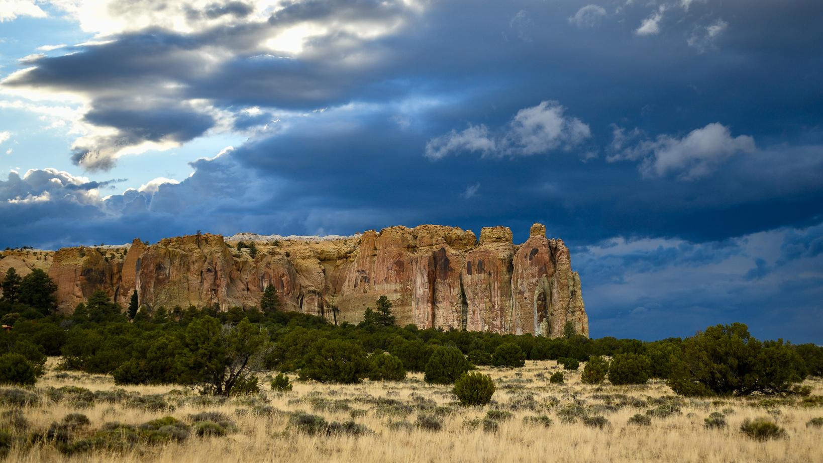 A dark stormy sky behind the sandstone bluff.