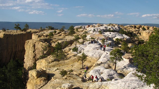 Hikers across the sandstone mesa top of the Headland Trail.