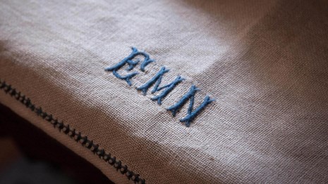 Natural light raking across a linen towel monogrammed EMN.