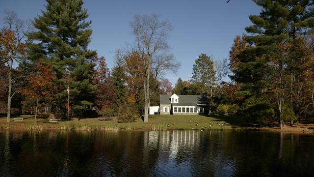 A cottage on the banks of a large pond.