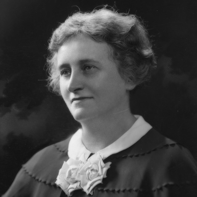 A woman wearing a dark dress with lace bow tie.