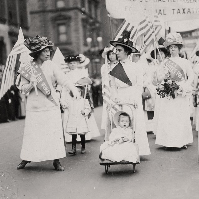 A parade of women and children carrying flags.