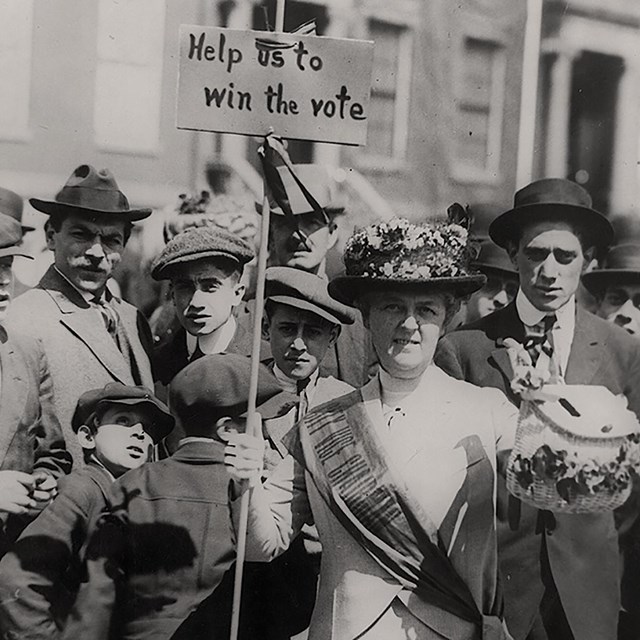 A woman holding a sign surrounded by a crowd of people.