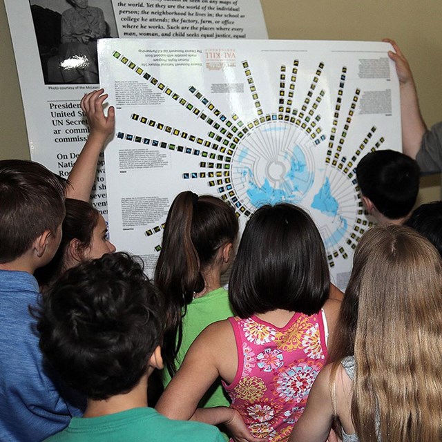 Students standing looking at diagram on a large piece of paper