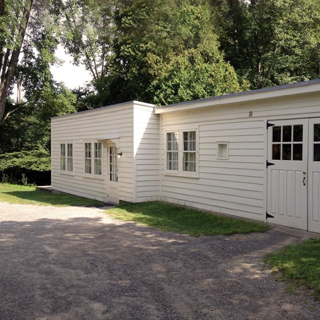 A single story white painted wood building with large windows and a double garage door.