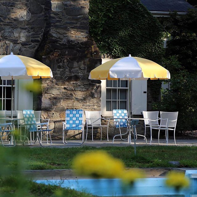 A pool and terrace with tables, chairs, and umbrellas.