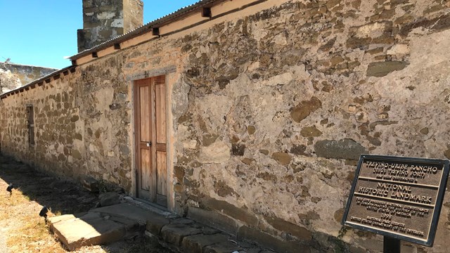 A one-story, long stucco weathered wall.