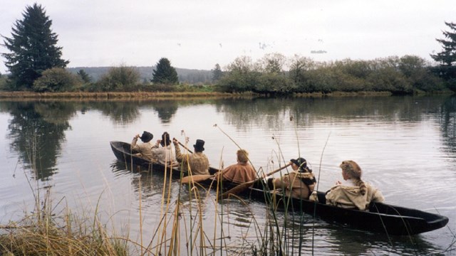 Hombres con ropa como Lewis y Clark en canoa