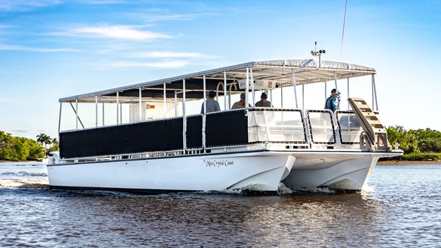 A tour boat on the water under a bright blue sky.