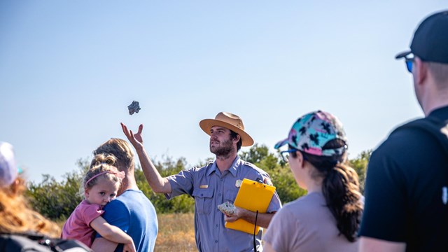 A ranger leads a walking program with a group of people.