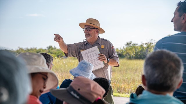 A ranger stands in front of a group of visitors.