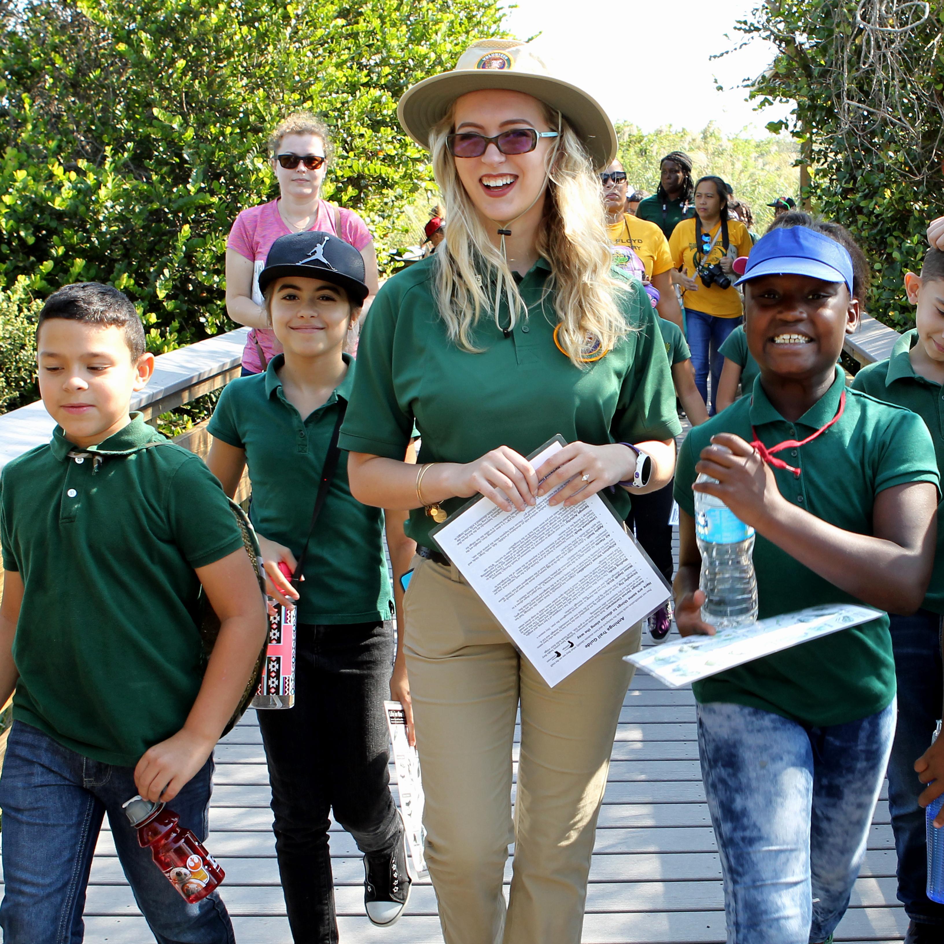 Students and adult walking walking down a boardwalk. 