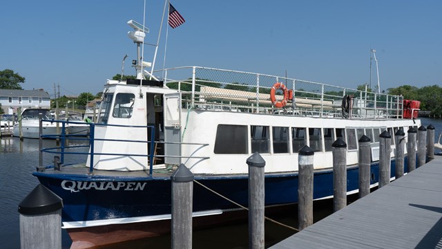 A red, white and blue painted ferry docked in a marina.