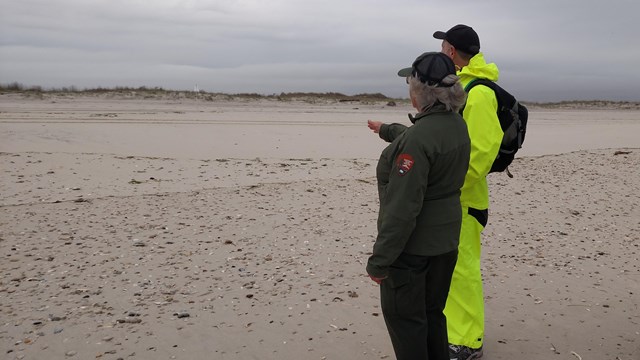 A park ranger stands near the breach on Fire Island with several onlookers. 