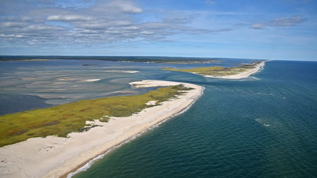 Aerial view of channel in barrier island and sandy shoals in the bay.