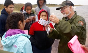 A group of children look on as a Park Ranger demonstrates how to use a water testing kit. 
