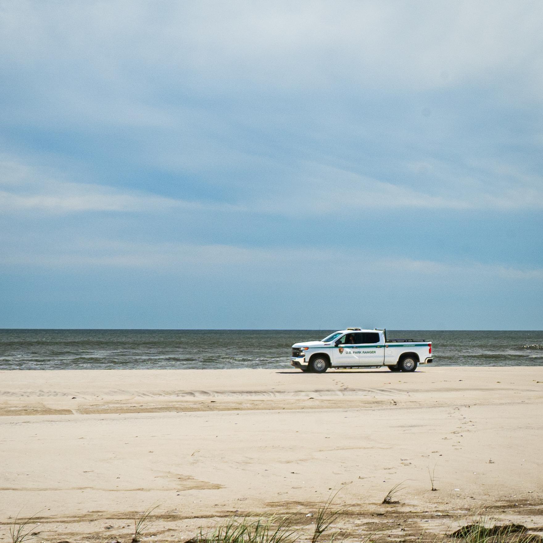 A law enforcement truck parked on an ocean beach.