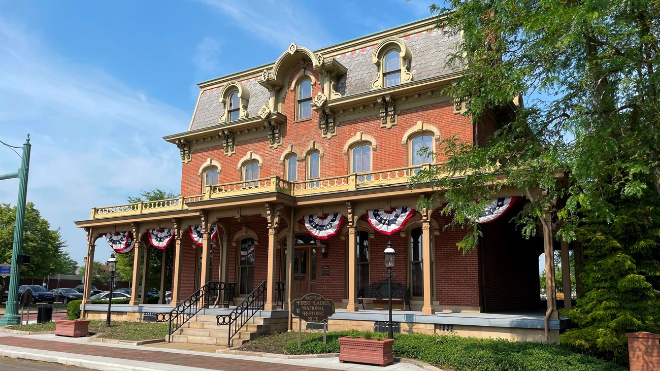Front of the Saxton House with red, white, and blue bunting between the 8 pillars on the front porch
