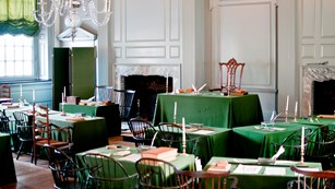 Assembly room with many tables covered with green tablecloths