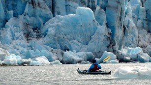 Person kayaking with glacier seen in the back