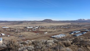 landscape showing remains of a relocation center, in the middle of a vast prairie with mountains