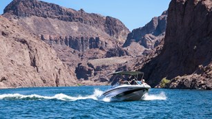 man boating on a lake through tall rocky mountains