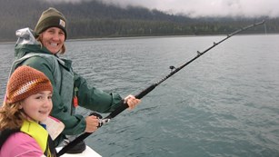 Adult and child fishing off the side of a boat