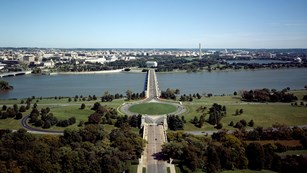Aerial view of traffic circle and bridge crossing a river towards DC monuments