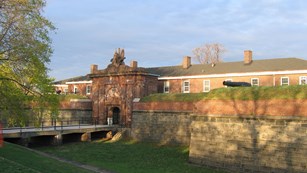 Morning sunlight illuminates the moat bridge and stone gatehouse of Fort Jay