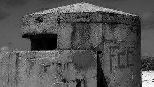 Black and white photo of a World War II pillbox on a beach