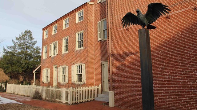 Sculpture of a raven in front of a three-story brick building
