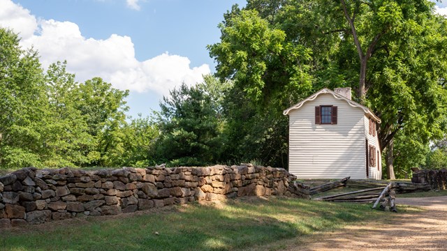 Small historic cabin next to a stone wall