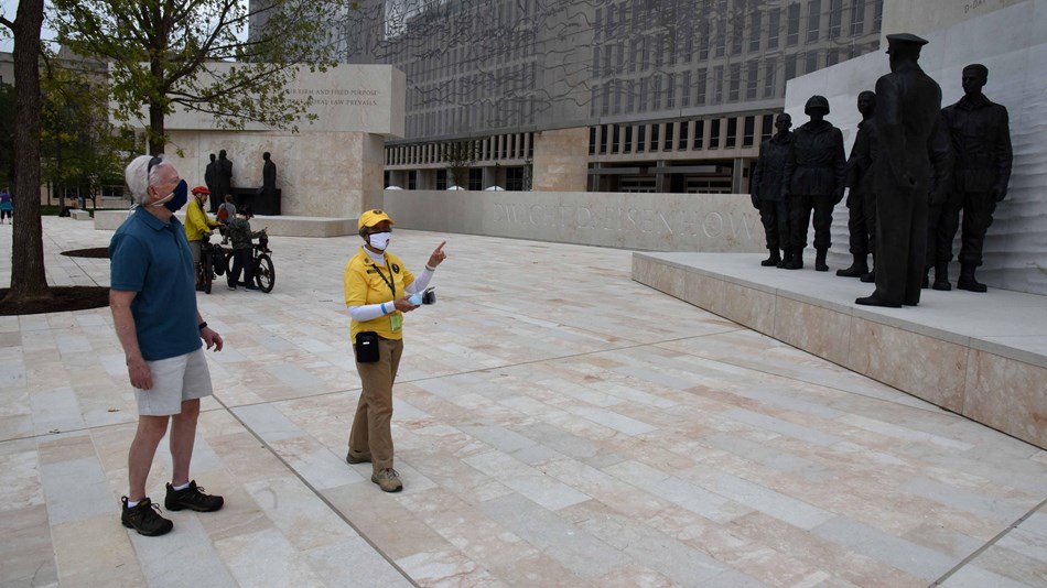 Volunteer talking to visitors on a memorial plaza