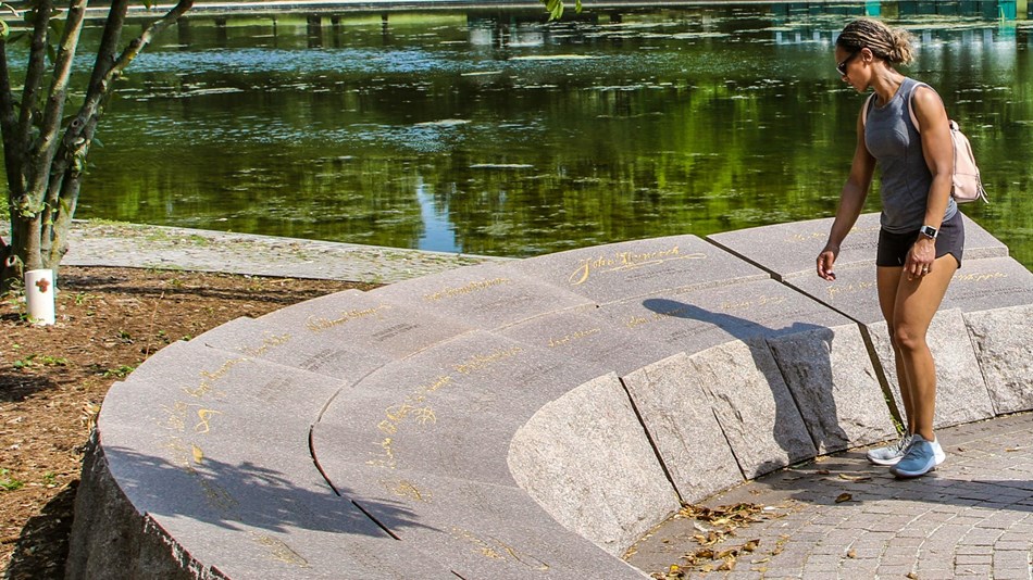 Visitor reading signatures engraved on a semi-circular stone memorial