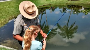 park ranger helping child fishing