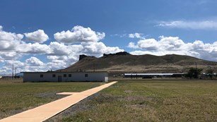 Several long buildings in a high desert near a bluff