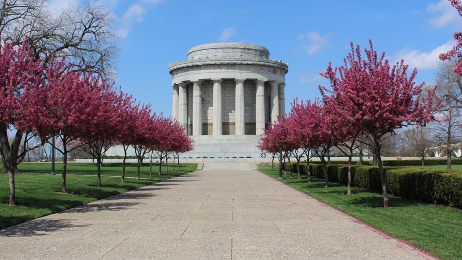 View of memorial rotunda down stone path flanked by pink flowering trees