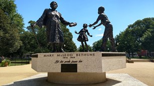 A statue of Mary McLeod Bethune handing her legacy to two young children.